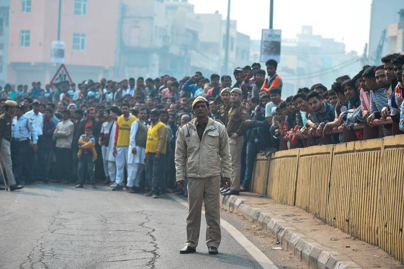A Police personnel stands guard along a road as onlookers gather following a factory fire in Anaj Mandi area of New Delhi. At least 43 people have died in a factory fire in India's capital New Delhi, with the toll still expected to rise.  AFP