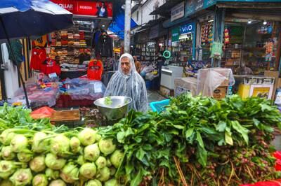 A vegetable seller waits for customers during a downpour in Srinagar, India. EPA