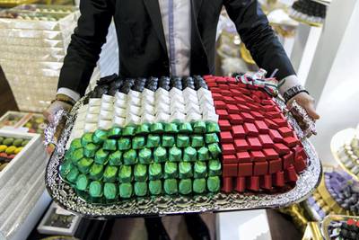 ABU DHABI, UNITED ARAB EMIRATES - NOV 1:Abdulaziz Diag, Morrrocan, 29, shows the offer UAE flag themed chocolate options available at the store he manages, Chocolate Boutique.(Photo by Reem Mohammed/The National)Reporter: Anna ZachariasSection: NA 