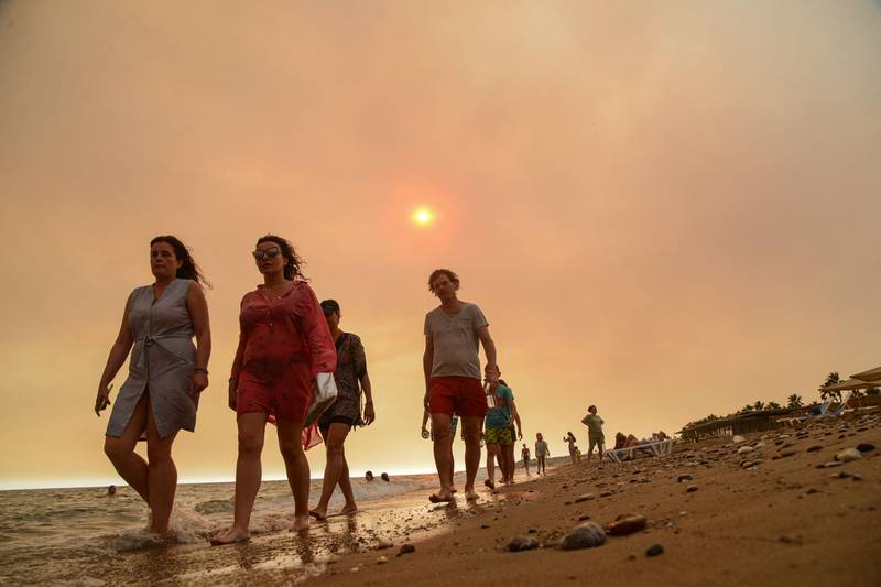 Tourists walk the beach as smoke shrouds the sun near Manavgat. Antalya mayor Muhittin Bocek said he suspected foul play as fires started in four places at once.