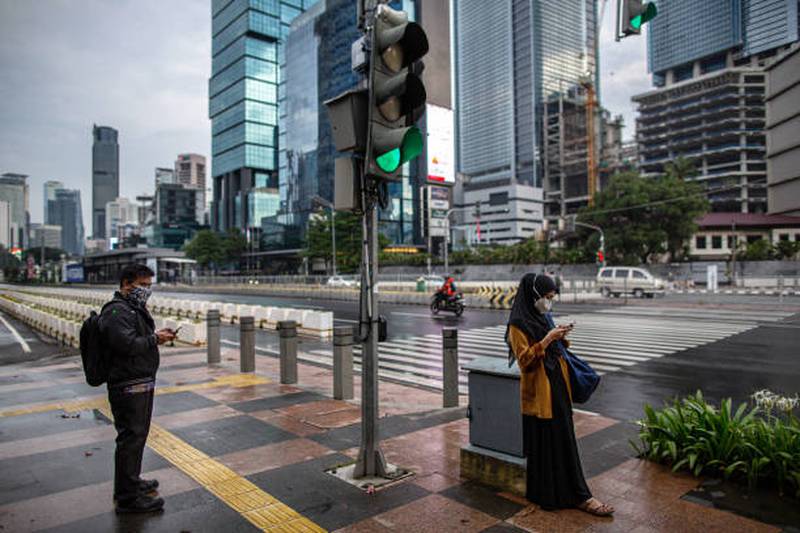 People wait to cross a road in Jakarta. Lockdowns and other measures to slow the spread of the coronavirus have weighed on Indonesia's economic activity, with the 
PMI for August showing a contraction in the country's manufacturing sector. Getty Images
