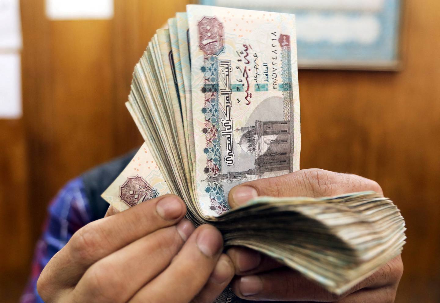 An exchange employee counting Egyptian notes in Cairo. The pound has lost close to 40 per cent of its value against the dollar since March. Reuters