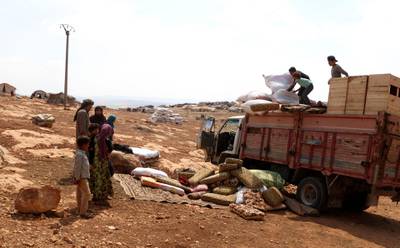 Displaced Syrians who fled from regime raids unload their belongings from a truck in a camp in Kafr Lusin near the border with Turkey in the northern part of Syria's rebel-held Idlib province.  AFP