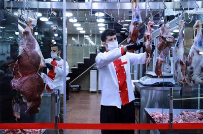 Butchers, wearing protective face masks, carve meat in the northeastern city of Sulaimaniyah, Iraq.   AFP
