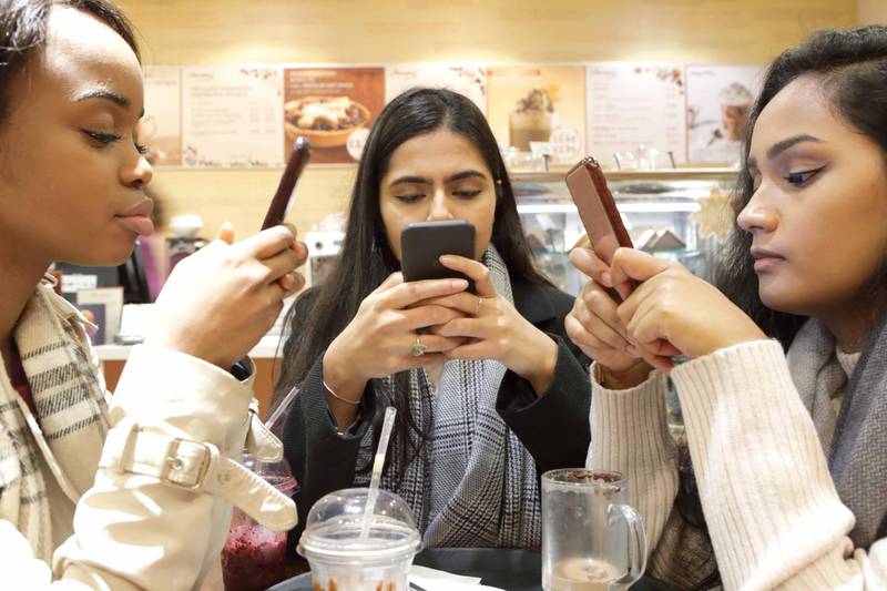 Three young woman on phones in cafe. Getty Images