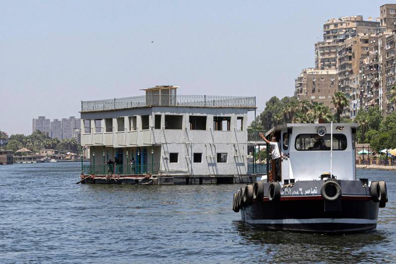 One of the houseboats usually moored on the Nile between Zamalek in Cairo and Agouza in Giza being towed away by authorities on June 27, 2022. AFP