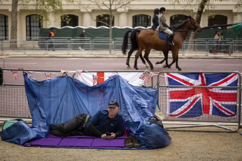 A royal fan takes a break after booking his spot on the coronation route in London. AP