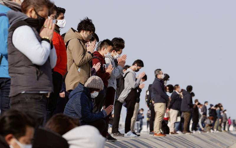 Participants pray and observe a moment of silence towards the sea at 2:46 p.m. (05:46 GMT), the time when the 9.0-magnitude earthquake struck off Japan's coast in 2011, at Arahama district in Sendai, northeastern Japan, March 11, 2021, to mark the 10-year anniversary of the 2011 earthquake and tsunami that killed thousands and set off a nuclear crisis.  Mandatory credit Kyodo/via REUTERS ATTENTION EDITORS - THIS IMAGE WAS PROVIDED BY A THIRD PARTY. MANDATORY CREDIT. JAPAN OUT. NO COMMERCIAL OR EDITORIAL SALES IN JAPAN.