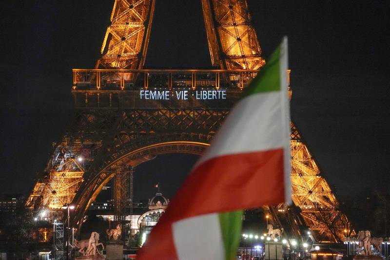 The Eiffel Tower lits the night with the a slogans "Woman, Life, Freedom" and "Stop Executions in Iran in support for the protests across Iran in Paris, Monday, January 16, 2023, as a Iranian flag flies next. AP