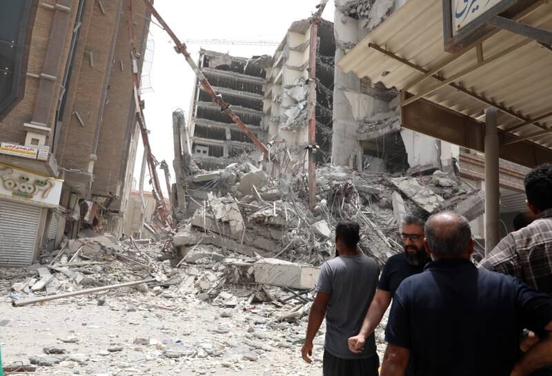 People stand at the site where a 10-storey building collapsed in the city of Abadan, Iran. EPA