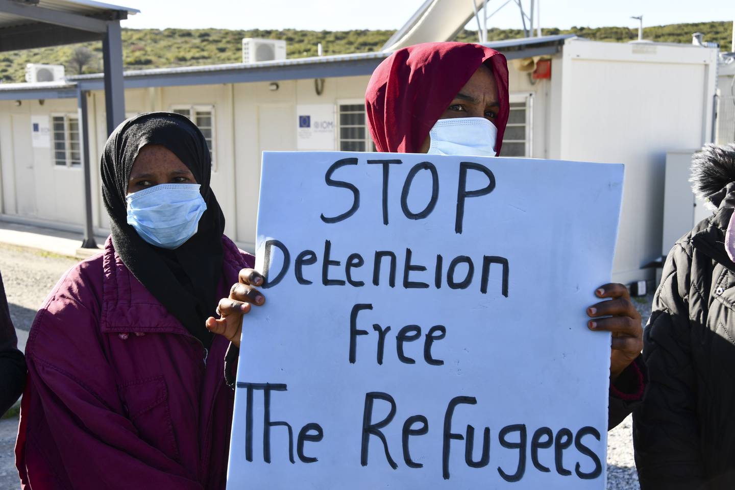 Asylum seekers hold banners during a visit at a camp by Valerie Pecresse on the eastern island of Samos, Greece. AP