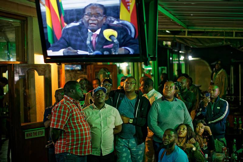 Zimbabweans watch a televised address to the nation by President Robert Mugabe at a bar in downtown Harare, Zimbabwe Sunday, Nov. 19, 2017. Zimbabwe's President Robert Mugabe has baffled the country by ending his address on national television without announcing his resignation. (AP Photo/Ben Curtis)