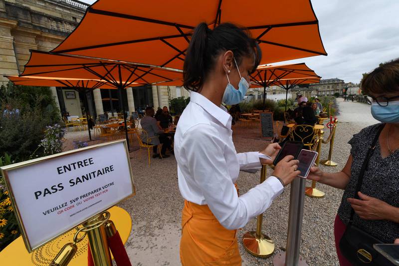 A restaurant owner checks a customer's health pass in Bordeaux France. AFP