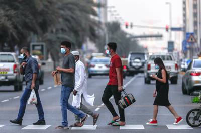 Abu Dhabi, United Arab Emirates, August 14, 2020.  Pedestrians with face masks cross the street at downtown Abu Dhabi on an early Friday evening.Victor Besa /The NationalSection:  NAFor:  Standalone/Stock Images