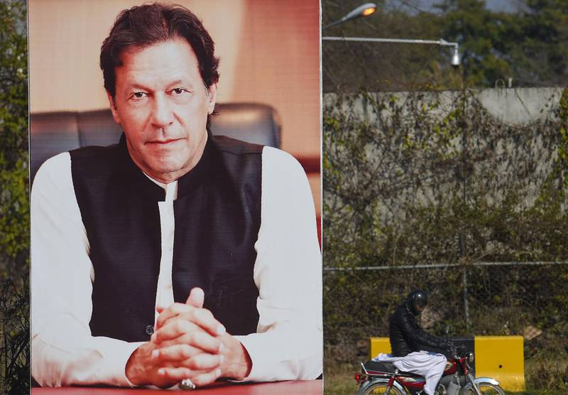 A Pakistani man rides past a poster displaying the portrait of Pakistani Prime Minister Imran Khan in Islamabad on February 19, 2019. Pakistan is ready to help India investigate the deadliest attack in Kashmir in decades, but will retaliate if Delhi attacks, Prime Minister Imran Khan said on February 19 as tensions between the nuclear-armed rivals soared. / AFP / FAROOQ NAEEM
