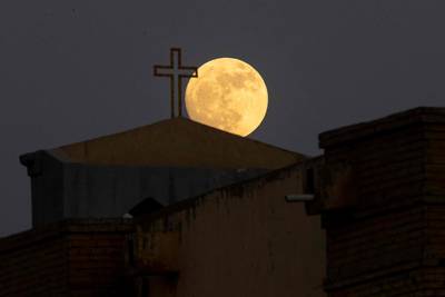The moon nears the end of its waxing gibbous phase as it rises above the Virgin Mary Chaldean Cathedral in Iraq's Basra. AFP