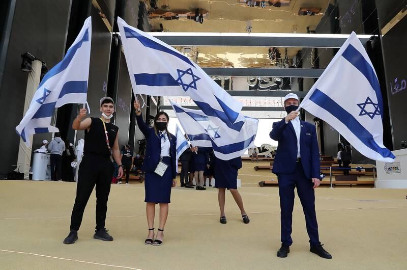 Staff members hold Israeli flags at the Expo 2020 site in Dubai.