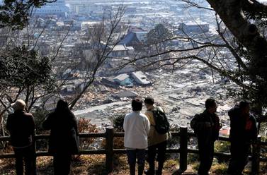 Survivors of the tsunami that devasted the Fukushima nuclear plant  look over the remains of Ishinomaki in Miyagi Prefecture, about 270km north of Tokyo. Japan is facing a choice over the future of its energy policy. Kimimasa Mayama / EPA