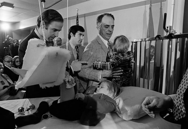 Joe Biden speaks with his bedridden son, Beau, before he was sworn in as the US senator from Delaware in January 1973. Mr Biden's first wife and daughter were killed in the car accident that injured his two sons. AP 