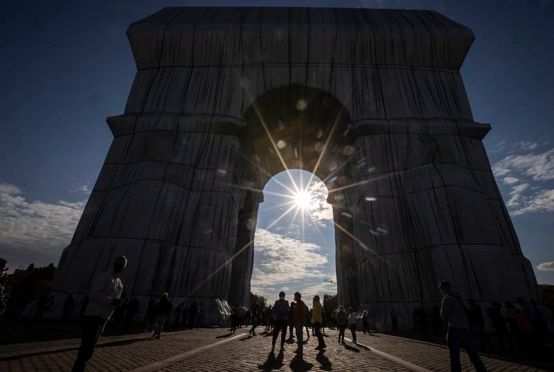The sun shines through the fully wrapped Arc de Triomphe monument. EPA