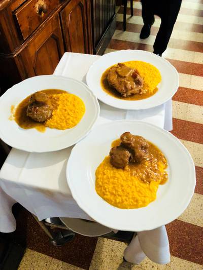 Three plates of saffron risotto and ossobuco, the typical dish of Milan, Italy