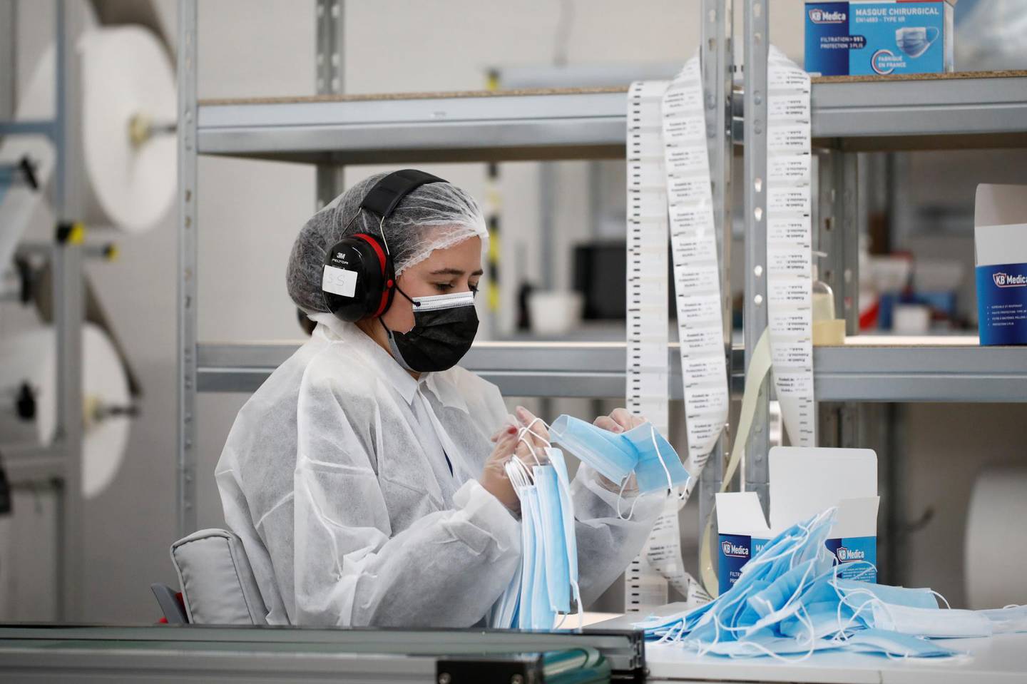 An employee gathers protective face masks from a production line conveyor at the KB MEDICA plant in Sartrouville, near Paris, as France tries to tackle a second wave of the coronavirus disease (COVID-19) outbreak, October 28, 2020. REUTERS/Benoit Tessier