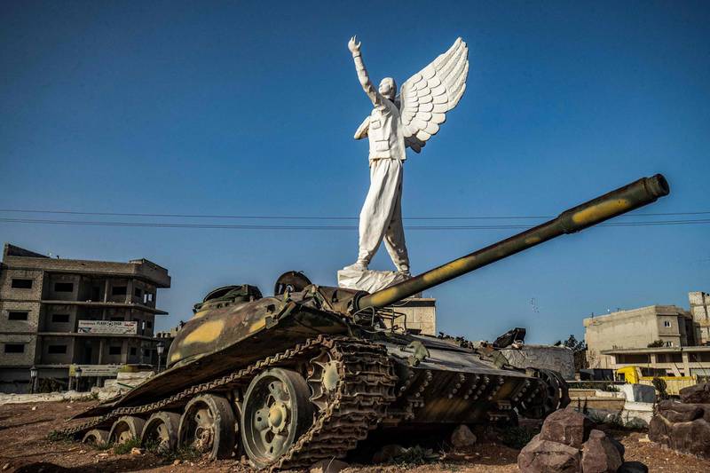 A buried tank next to the 'Free Woman' statue in the town of Kobani, Aleppo province, is a monument to 10 years of violence in Syria. AFP