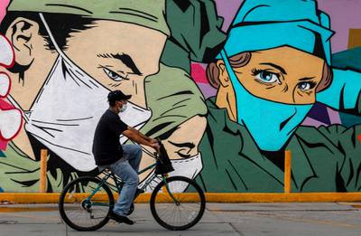 A man rides past a coronavirus-related mural by urban artists Mick Martinez and "Were Torres" in Ciudad Juarez, Chihuahua state, Mexico. AFP