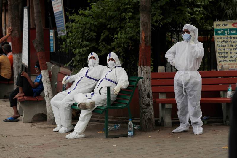 People wearing personal protective suits wait to cremate the body of their relative who died of COVID-19, in New Delhi, India, Friday, June 5, 2020. The coronavirus pandemic is leaving India's morgues piling up with the dead and graveyards and crematoriums overwhelmed. Like elsewhere in the world, the virus has made honoring the dead in New Delhi a hurried affair, largely devoid of the rituals that give it meaning for mourners. (AP Photo/Manish Swarup)