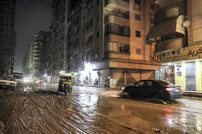 A tuktuk (motorised rickshaw) and a car drive through heavy mud along a street in the Faisal district of the Egyptian capital's twin city of Giza late on October 22, 2019. - Rare heavy rains disrupted traffic across the Egyptian capital Cairo and caused delays in flights late night on October 22, airport officials said. Prime Minister Mostafa Madbouli also announced the closure of universities and schools in some areas of Cairo, Giza and Qalyubia following bad weather forecasts from the country's Meteorological Authority. (Photo by Mohamed el-Shahed / AFP)