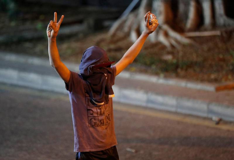 An anti-government protester holds stones, as he flashes victory signs during a protest near the parliament square. AP