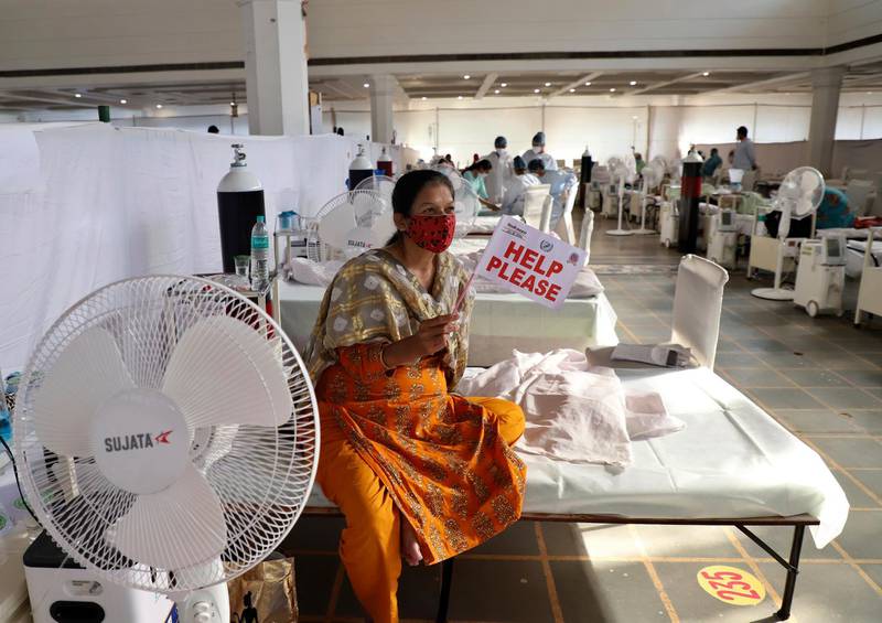 A patient receiving treatment at a free Covid-19 centre in New Delhi displays a placard asking for help from volunteers. The centre is run by a Sikh voluntary organisation. AP Photo