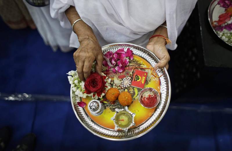 A woman holds a plate with rakhis, sweets and oil lamps. AP