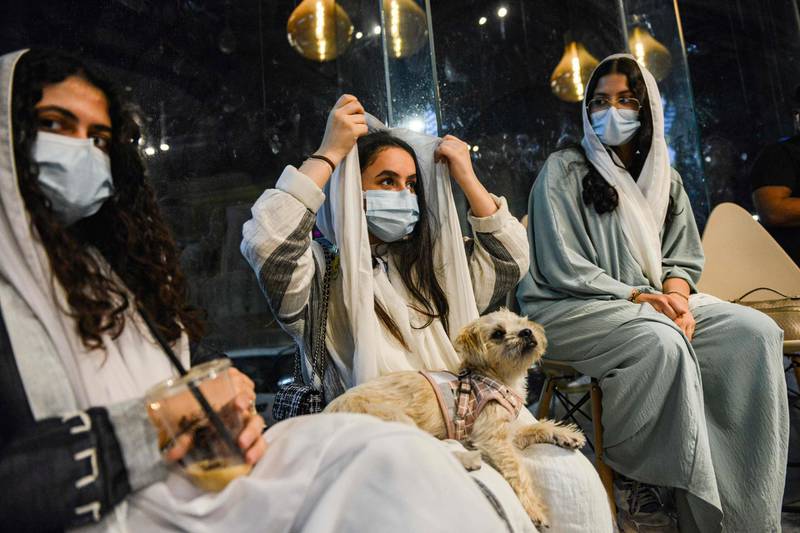 A woman adjusts her headdress as she sits with her dog at the Barking Lot cafe. AFP
