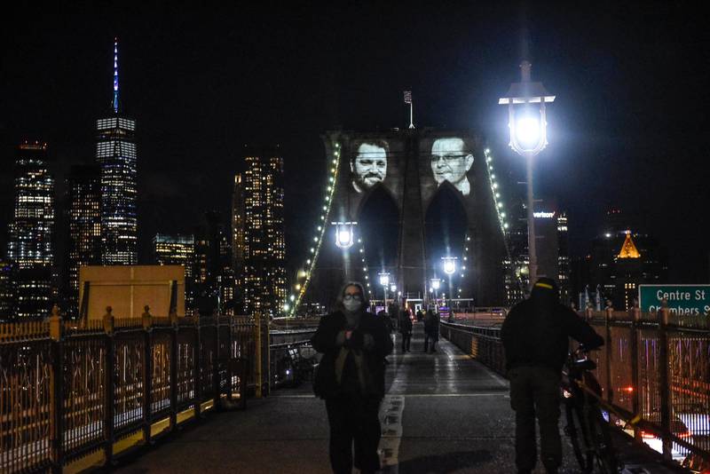 NEW YORK, NY - MARCH 14: Images of New Yorkers lost to the COVID-19 pandemic are projected on to the Brooklyn Bridge on March 14, 2021 in New York City. New York City honors lives lost to COVID-19 on the anniversary of the one year anniversary of the COVID-19 lockdown.   Stephanie Keith/Getty Images/AFP
== FOR NEWSPAPERS, INTERNET, TELCOS & TELEVISION USE ONLY ==
