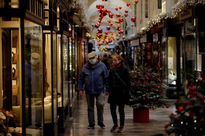 People wearing face masks walk past Christmas trees and decorations in Burlington Arcade, where all non-essential shops are temporarily closed during England's second coronavirus lockdown, in London, Wednesday, Nov. 25, 2020. With major COVID-19 vaccines showing high levels of protection, British officials are cautiously â€” and they stress cautiously â€” optimistic that life may start returning to normal by early April. (AP Photo/Matt Dunham)