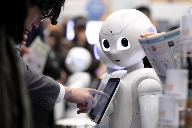 An attendee tries out an application on a SoftBank Group Corp. Pepper humanoid robot at the SoftBank Robot World 2017 in Tokyo, Japan, on Tuesday, Nov. 21, 2017. SoftBank Chief Executive Officer Masayoshi Son has put money into robots, artificial intelligence, microchips and satellites, sketching a vision of the future where a trillion devices are connected to the internet and technology is integrated into humans.  Photographer: Kiyoshi Ota/Bloomberg