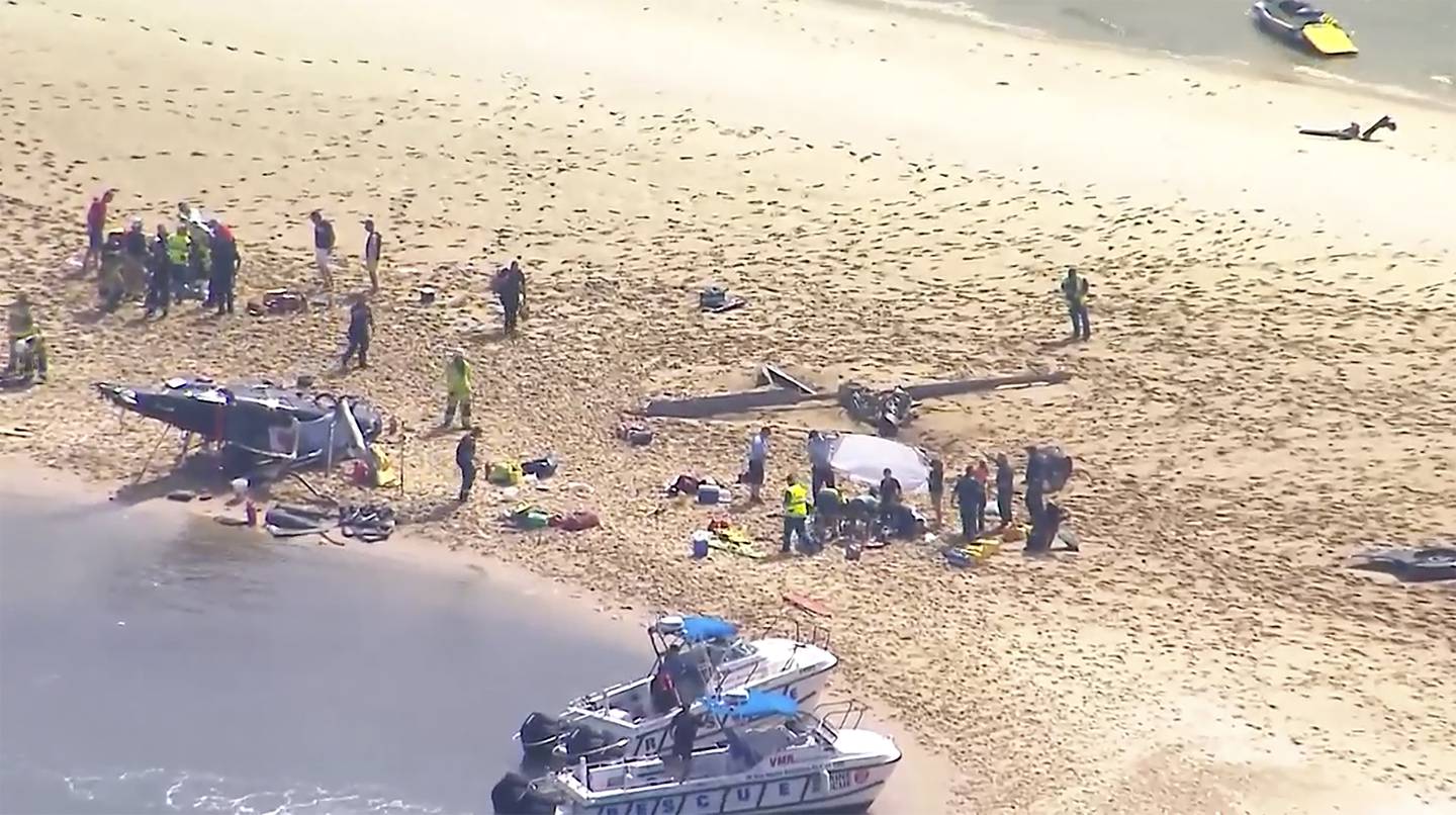The crashed helicopter, victims and emergency services on a sandbank at Queensland's Gold Coast. AP