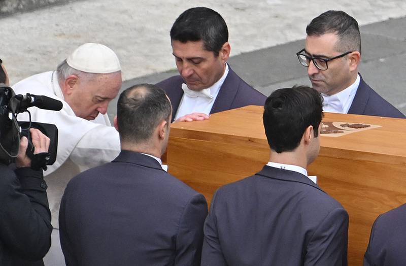 Pope Francis pays his respects as he touches the coffin. AFP