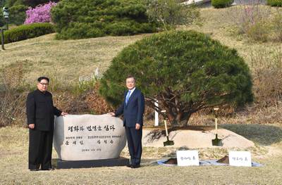 North Korea's leader Kim Jong Un (L) and South Korea's President Moon Jae-in (R) pose in front of a stone inscribed "Peace and Prosperity Are Planted" as they participate in a tree-planting ceremony next to the Military Demarcation Line that forms the border between the two Koreas at the truce village of Panmunjom.
North Korean leader Kim Jong Un and the South's President Moon Jae-in sat down to a historic summit on April 27 after shaking hands over the Military Demarcation Line that divides their countries in a gesture laden with symbolism. / AFP PHOTO / Korea Summit Press Pool