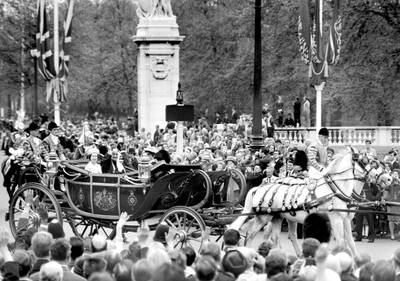King Faisal of Saudi Arabia waves in response to the crowd lining the Mall as he drives with the Queen to Buckingham Palace on arrival for his eight-day state visit.