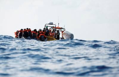 Crew members of the Geo Barents migrant rescue ship, operated by Doctors Without Borders, distribute life jackets to a group of 61 migrants on a wooden boat in international waters off the coast of Libya, in the central Mediterranean Sea, on September 28. Reuters