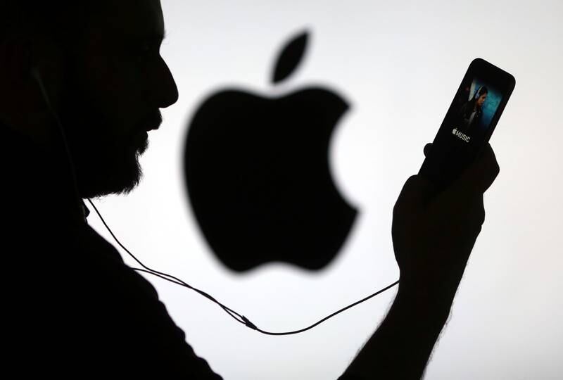 A man checks the Apple Music streaming site using his Apple Inc. iPhone 6s as he stands framed against a wall bearing the Apple logo in this arranged photograph in London, U.K., on Wednesday, Dec. 23, 2015. Beatles songs will now be available around the world on nine streaming services including Apple, Spotify, Deezer and Google Play, the bands record company, Vivendi SAs Universal Music Group, said Wednesday in a statement. Photographer: Chris Ratcliffe/Bloomberg