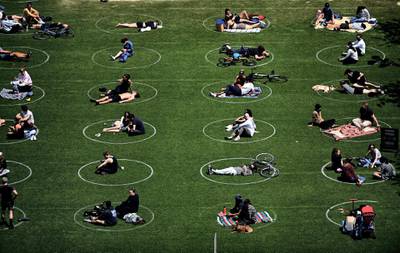 People are seen practising social distancing in white circles in Domino Park, during the Covid-19 pandemic on May 17, 2020 the in Brooklyn borough of New York City. (Photo by Johannes EISELE / AFP)