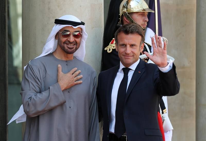 The Emirati and French presidents wave in the courtyard of the Elysee Palace.