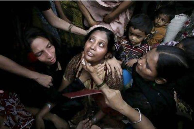 People comfort a woman who lost a family member in a garment factory fire during a funeral in Karachi.