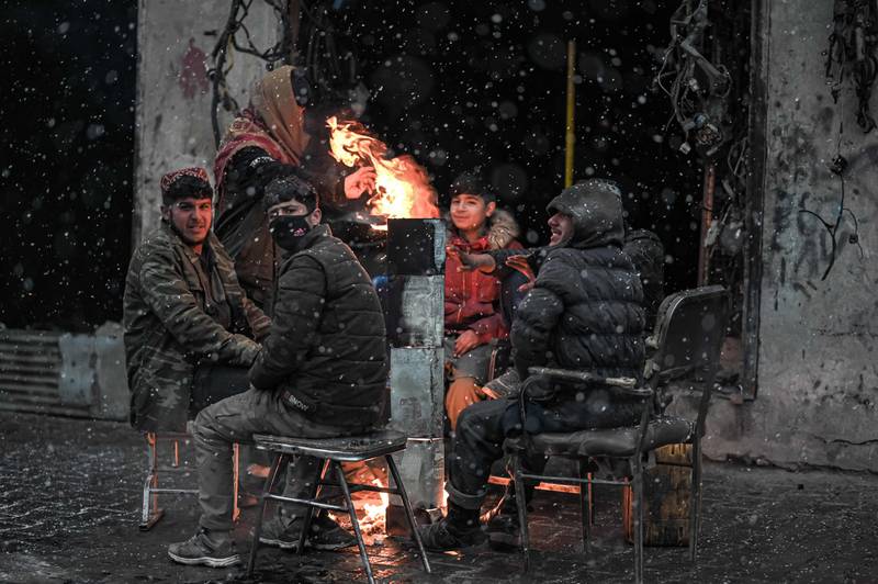Youths gather around a fire to enjoy the weather.