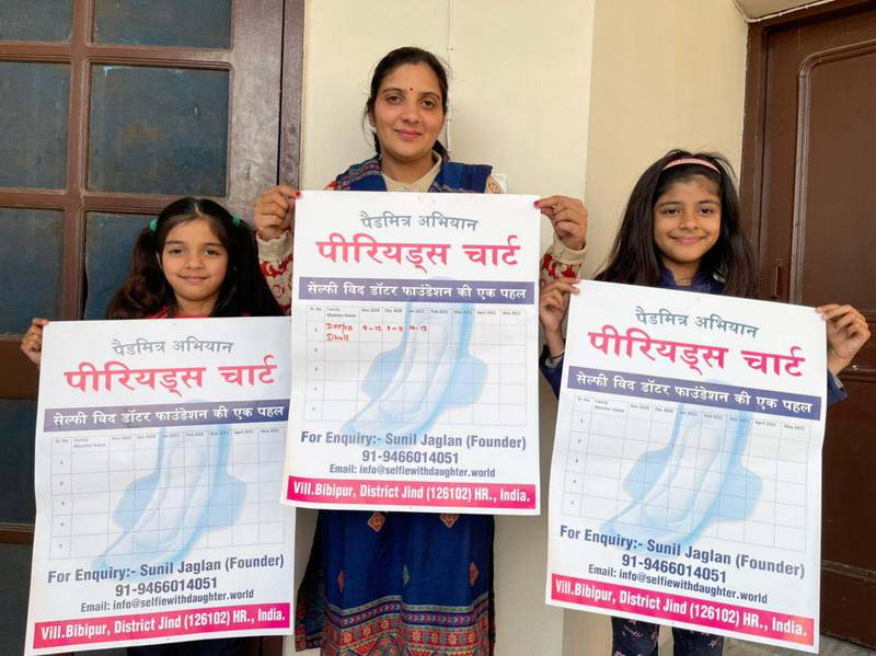 Deepa Dhull posing with her daughters Yachika, 6, and Nandini, 9, holding period charts.