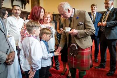 King Charles shakes hands with a boy as he visits Aberdeen Town House to meet families who have settled in Aberdeen from Afghanistan, Syria and Ukraine in October 2022