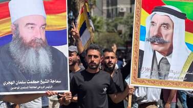 Protesters hold photos of Druze spiritual leader Sheikh Hikmat Al Hajari, left, and late leader Sultan Al Atrash during a protest in the Druze-majority city of Suweida. EPA